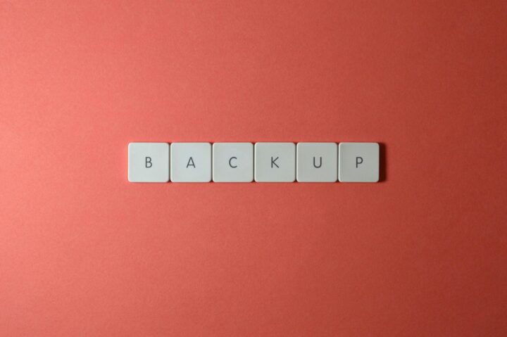 Free Close-up of keyboard keys spelling 'BACKUP' placed on a coral-colored surface. Stock Photo
